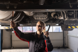 Mecánica de Renault Trucks inspecciona los bajos de un camión elevado con una linterna durante una revisión en taller.